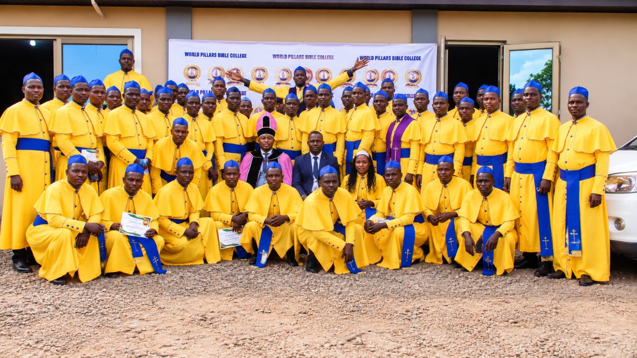 Graduands in yellow and blue ceremonial robes gathered for a group photograph outside the college building