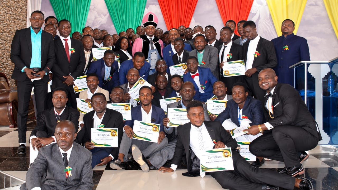Graduates holding their certificates together for a group photograph inside the auditorium